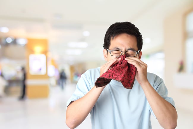 man sneezing into tissue